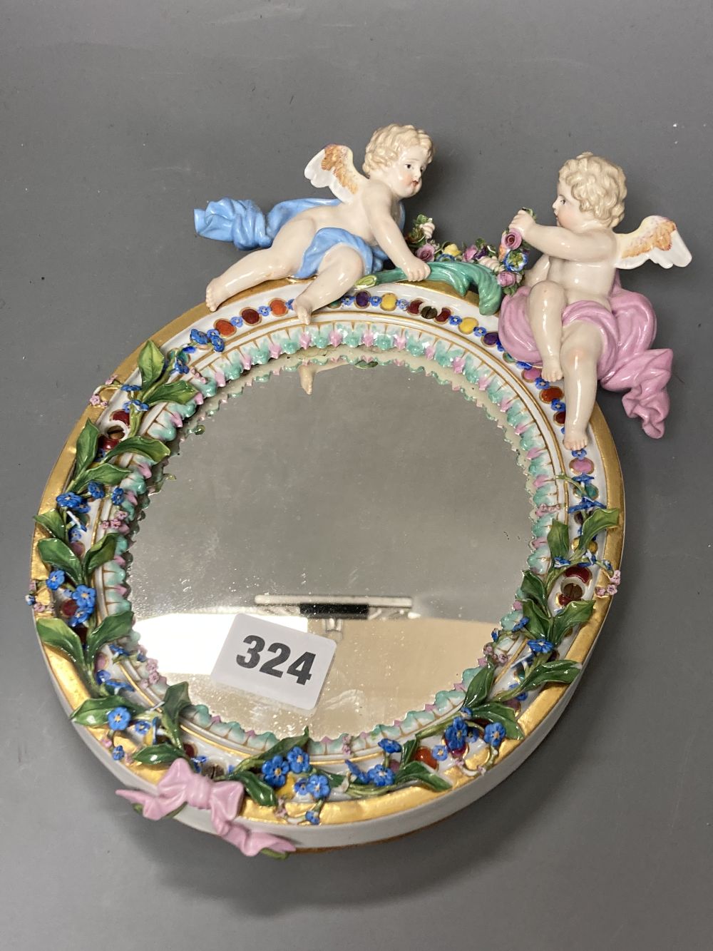 A 19th century Meissen porcelain framed oval mirror surmounted with two angelic figures, height 22cm